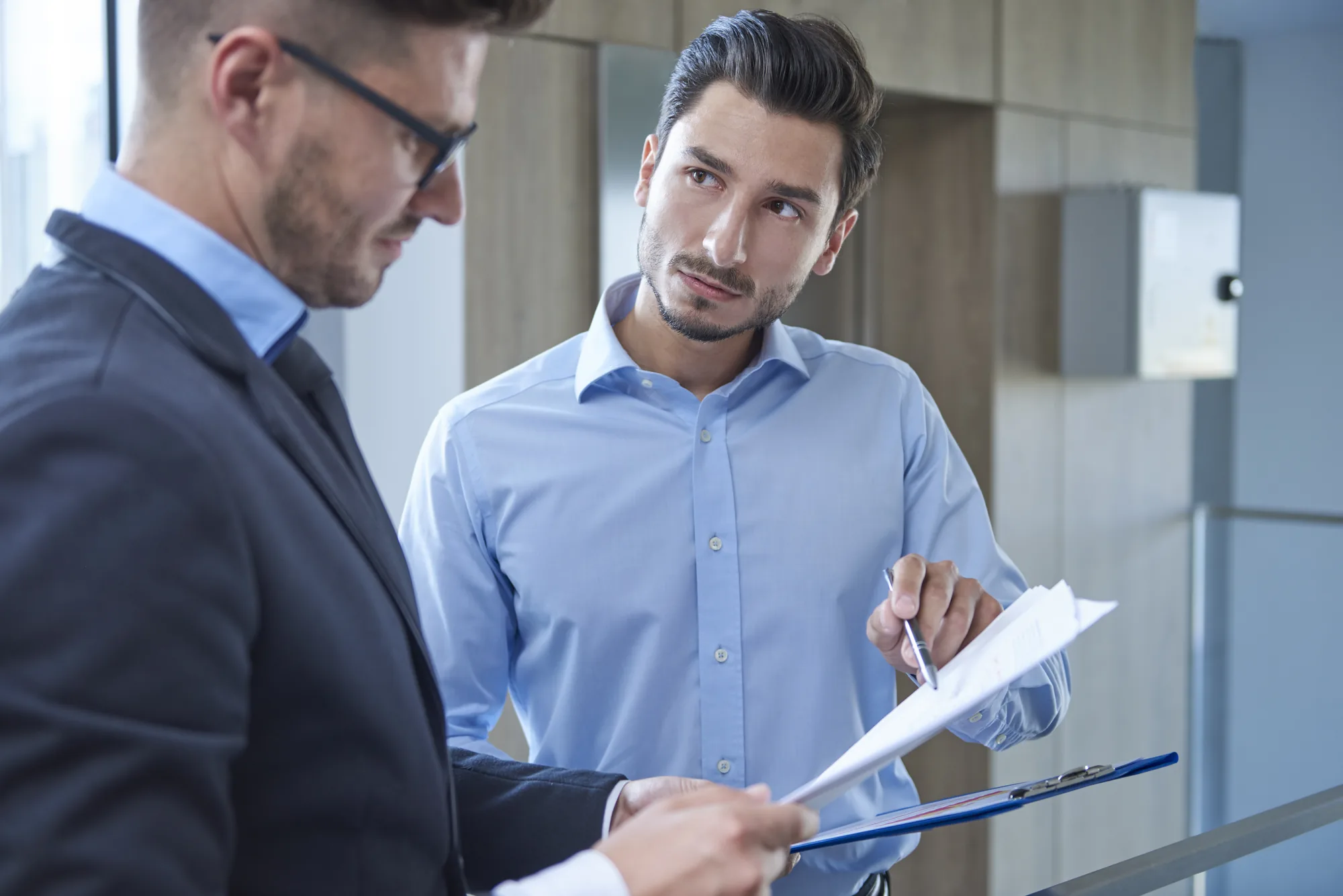 Two people at a desk going through a clipboard of papers together